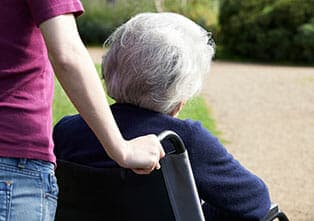 Person Pushing an Elderly Person in a Wheelchair